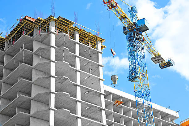 Crane and building under construction against blue sky Crane and building under construction against blue sky